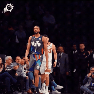 A Basketball Player Wearing A Suns Jersey Talks To Another Player GIF