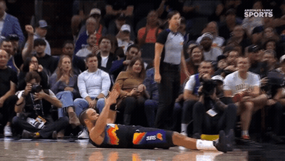 A Basketball Player Wearing A Suns Uniform Is Laying On The Floor GIF