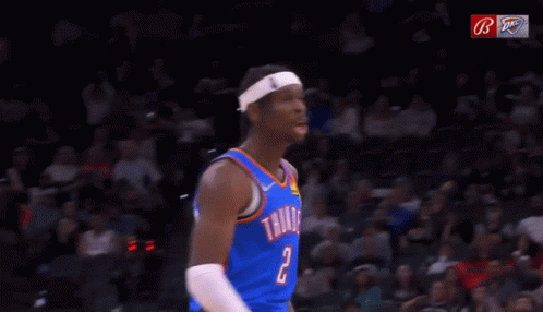 A Basketball Player Wearing A Thunder Jersey Is Yawning In Front Of A Crowd During A Game . GIF