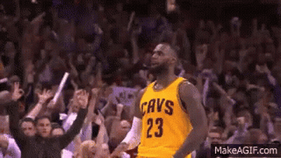 A Basketball Player Wearing A Yellow Cavs Jersey Is Standing In Front Of A Crowd Of People . GIF