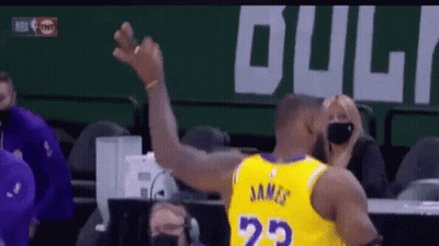 A Basketball Player Wearing A Yellow Jersey With The Number 23 On The Back Is Raising His Arm In The Air . GIF