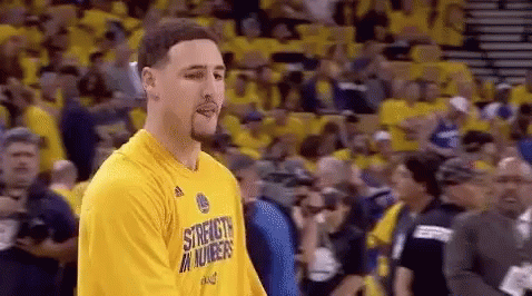 A Basketball Player Wearing A Yellow Shirt Is Standing In Front Of A Crowd Of People . GIF