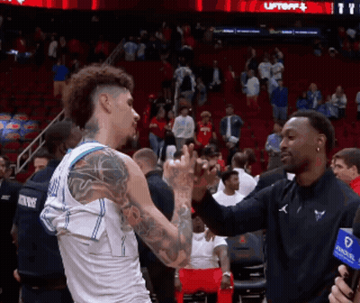 A Basketball Player With A Tattoo On His Arm Shakes Hands With Another Man GIF