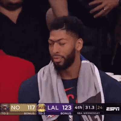 A Basketball Player With A Towel Around His Neck Sits In The Stands During A Game GIF