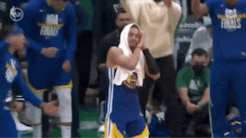A Basketball Player With A Towel Wrapped Around His Head Is Standing In Front Of A Crowd Of People . GIF