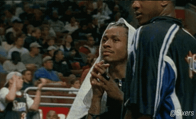 A Basketball Player With A Towel Wrapped Around His Head Stands Next To Another Player . GIF