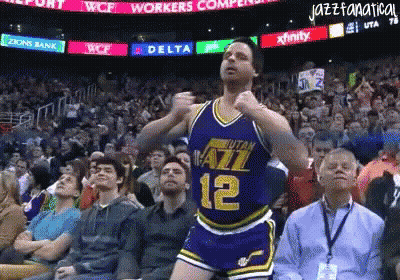 A Basketball Player With The Number 12 On His Jersey Is Dancing In Front Of A Crowd GIF