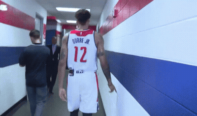 A Basketball Player With The Number 12 On His Jersey Is Walking Down A Hallway GIF