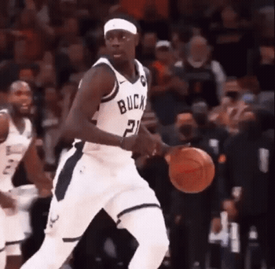 A Basketball Player With The Number 21 On His Jersey Is Dribbling A Basketball During A Game . GIF