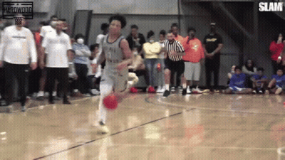 A Basketball Player With The Number 7 On His Jersey Is Dribbling The Ball On A Court GIF