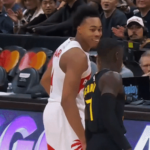 A Basketball Player With The Number 7 On His Jersey Stands Next To Another Player GIF
