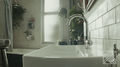 A Bathroom With A Sink And A Window With Plants Hanging On The Wall GIF