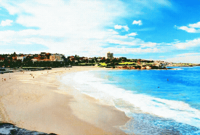 A Beach With A City In The Background And A Blue Sky GIF
