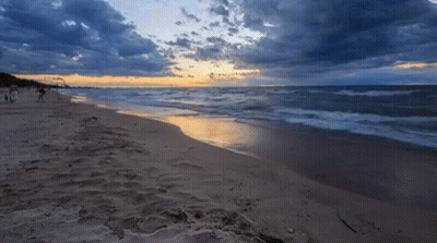 A Beach With A Sunset In The Background GIF