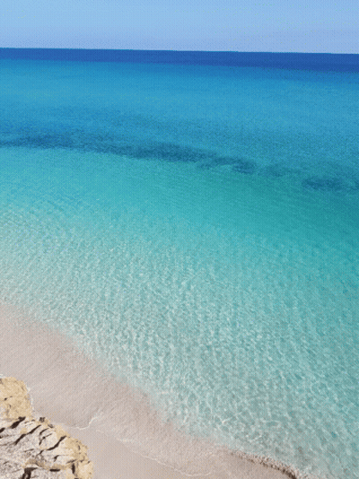 A Beach With Turquoise Water And A Blue Sky GIF