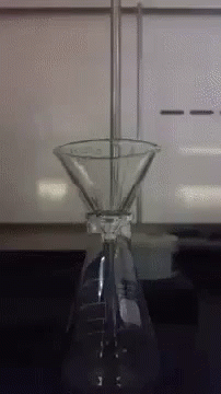 A Beaker With A Funnel Attached To It Is On A Table GIF