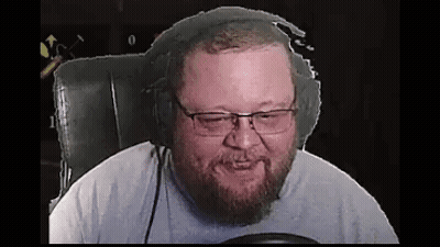A Bearded Man Wearing Headphones And Glasses Is Sitting In A Chair . GIF