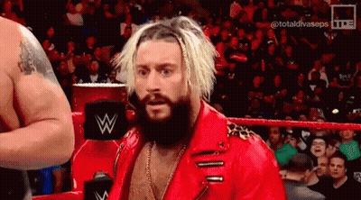 A Bearded Wrestler In A Red Jacket Is Standing In A Ring . GIF