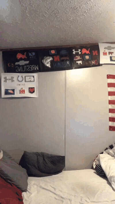 A Bed In A Dorm Room With A Bunch Of Stickers On The Wall GIF