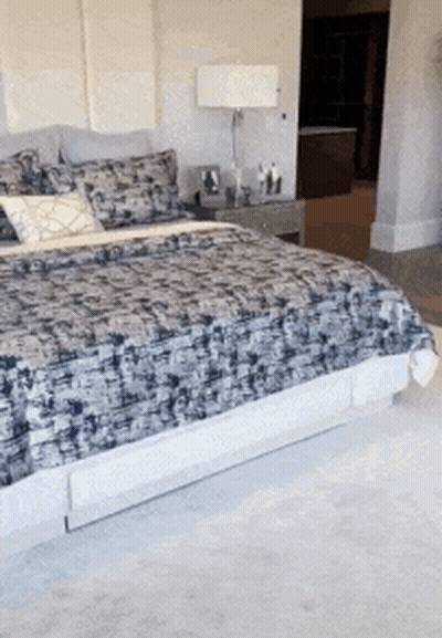 A Bed With A Patterned Blanket And Pillows In A Bedroom GIF