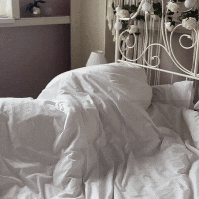 A Bed With White Sheets And Pillows And A White Headboard GIF