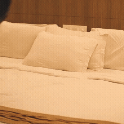 A Bed With White Sheets And Pillows In A Bedroom GIF