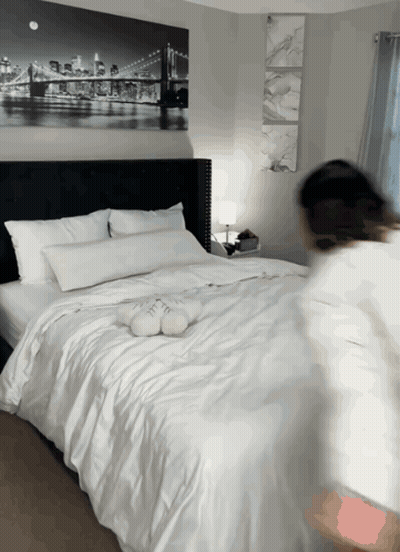 A Bed With White Sheets And Pillows In A Bedroom With A Painting Of A Bridge On The Wall GIF