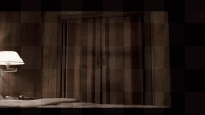 A Bedroom With A Bed And A Lamp And A Striped Door GIF