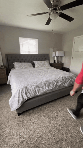 A Bedroom With A Ceiling Fan Above The Bed GIF