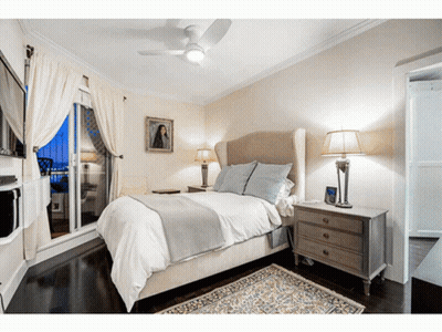 A Bedroom With A Ceiling Fan And A Painting On The Wall GIF