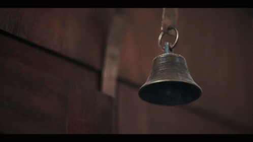 A Bell Is Hanging From A Chain On A Wooden Surface GIF