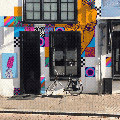 A Bicycle Is Parked In Front Of A Building With A Colorful Mural GIF