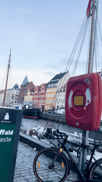 A Bicycle Is Parked Next To A Sign That Says Affald GIF
