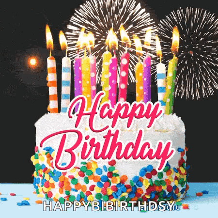 A Birthday Cake With Candles And Fireworks Behind It . GIF