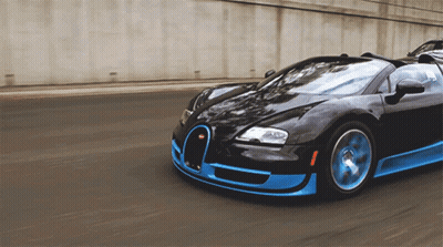 A Black And Blue Sports Car Is Driving Down A Street GIF
