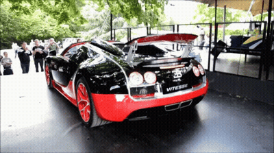 A Black And Red Bugatti Vitesse Is Parked In Front Of A Crowd Of People GIF