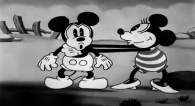 A Black And White Cartoon Of Mickey Mouse And Minnie Mouse Standing Next To Each Other On A Beach . GIF