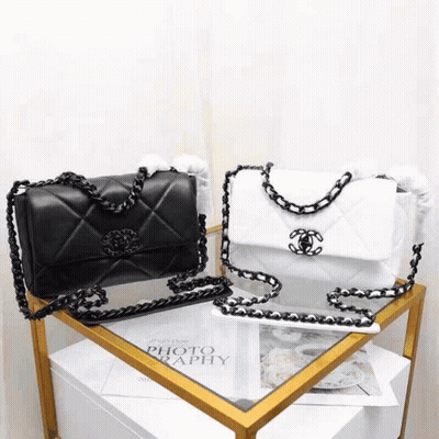 A Black And White Chanel Purse Is Sitting On Top Of A Table . GIF