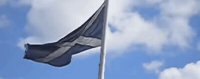 A Black And White Flag Is Waving In The Wind Against A Blue Sky With Clouds GIF