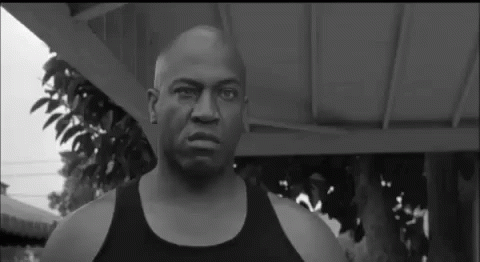 A Black And White Photo Of A Bald Man Wearing A Black Tank Top . GIF