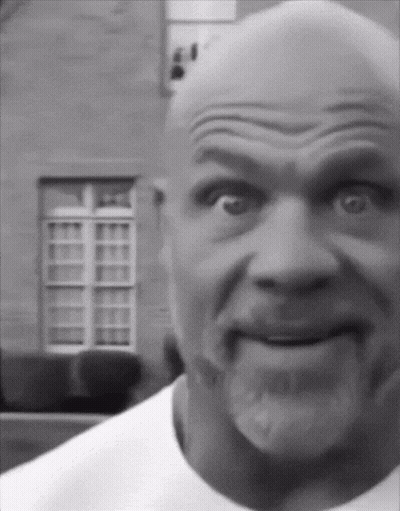 A Black And White Photo Of A Bald Man With A Beard Making A Funny Face GIF