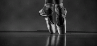 A Black And White Photo Of A Ballerina 'S Feet In Pointe Shoes Jumping In The Air . GIF