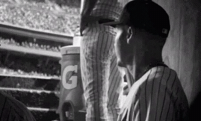 A Black And White Photo Of A Baseball Player In A Dugout . GIF