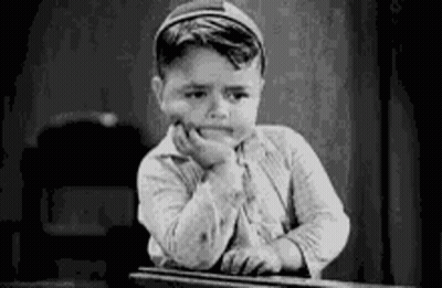 A Black And White Photo Of A Boy Sitting At A Desk With His Hand On His Chin . GIF