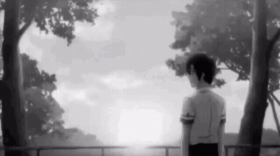 a black and white photo of a boy standing in front of a fence looking at the sun .