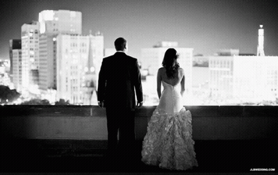 A Black And White Photo Of A Bride And Groom Looking At A City Skyline GIF