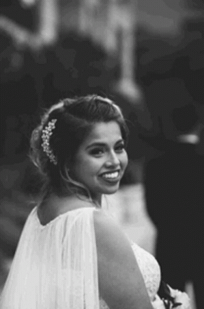 A Black And White Photo Of A Bride In A Wedding Dress And Veil Smiling . GIF