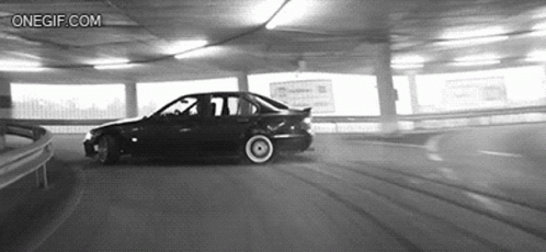 A Black And White Photo Of A Car Driving Down A Parking Garage . GIF