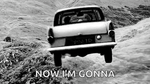 A Black And White Photo Of A Car Flying Through The Air On A Dirt Road . GIF