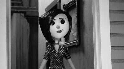 A Black And White Photo Of A Cartoon Doll In A Polka Dot Dress Standing In A Doorway . GIF